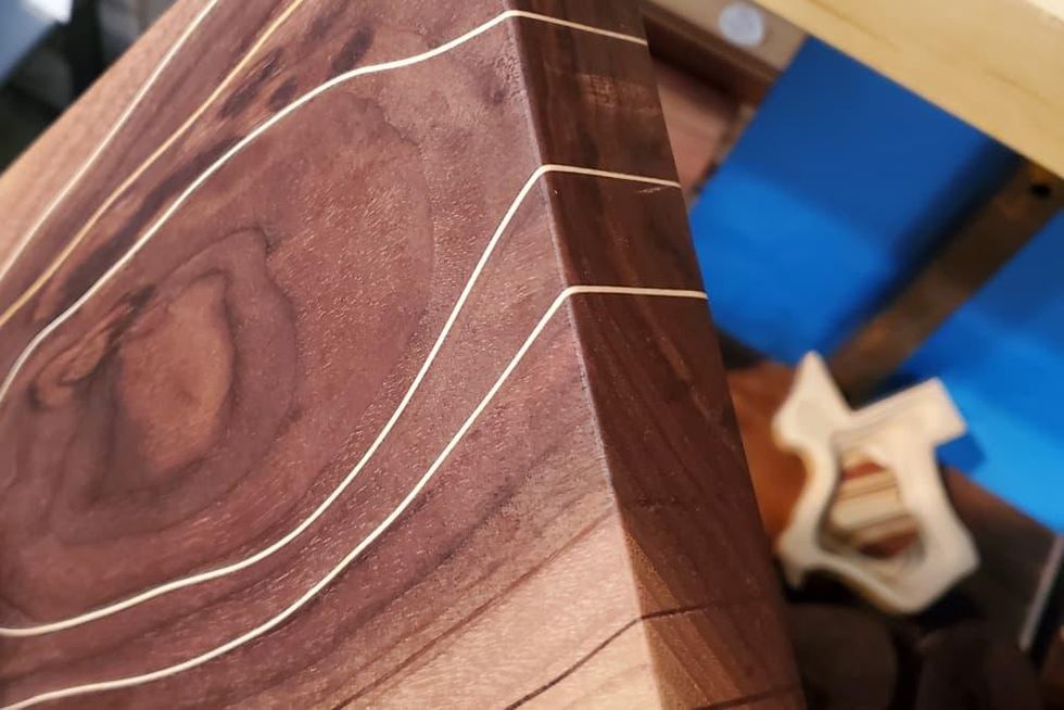 A close-up of a wood cutting board with an organic line inlay.