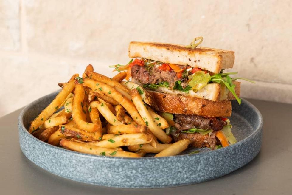 A cross-section of a braised pork sandwich with fries.