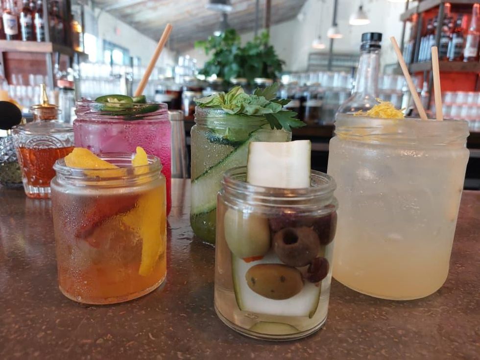 A green drink with basil and cucumber garnishes