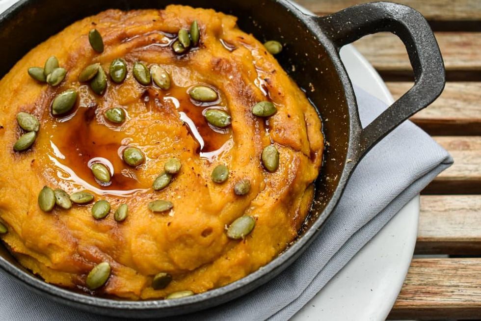 A ramekin of pumpkin hummus garnished with pumpkin seeds from Aba.
