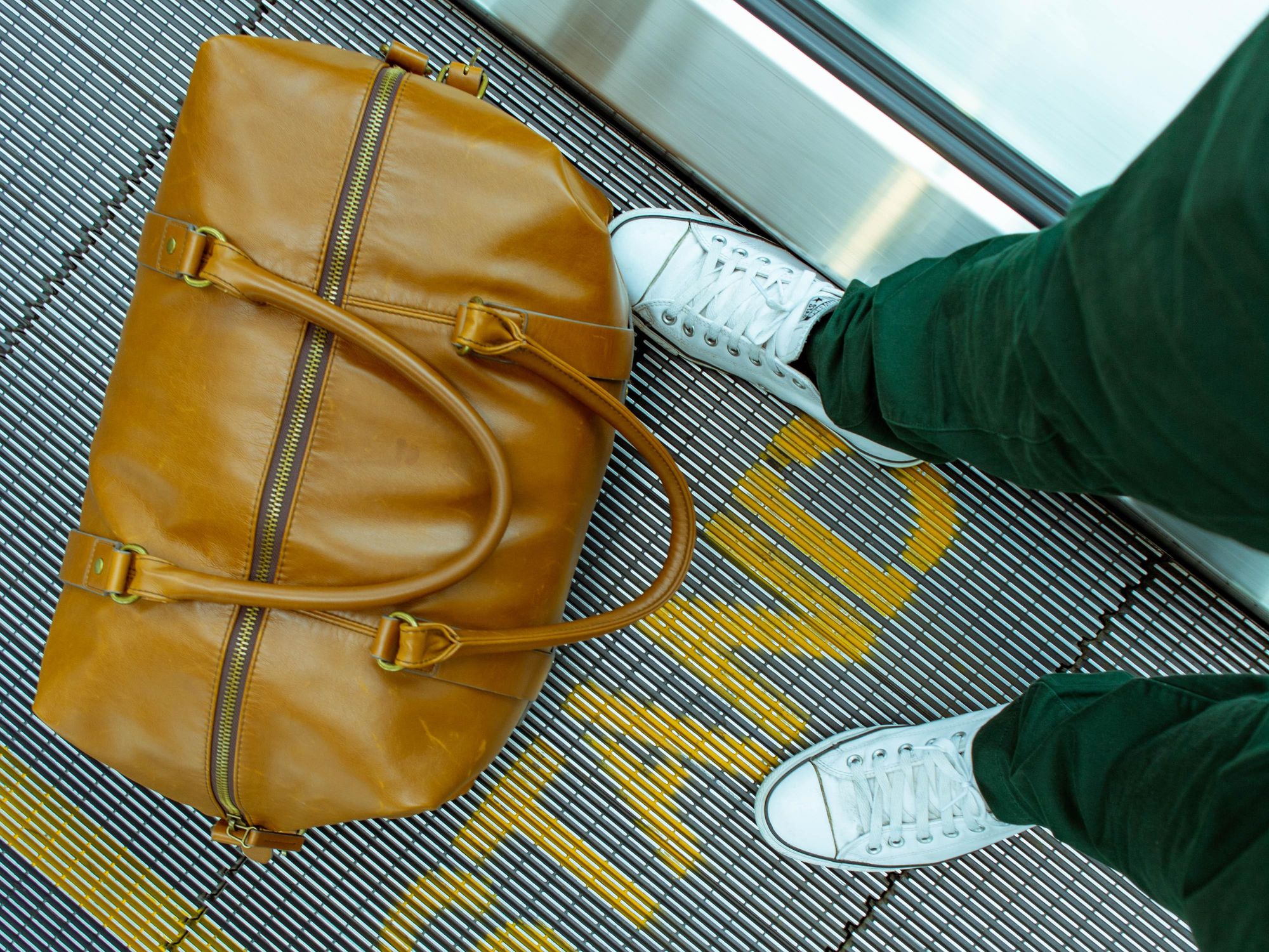 airport travel person stranding beside brown leather handbag