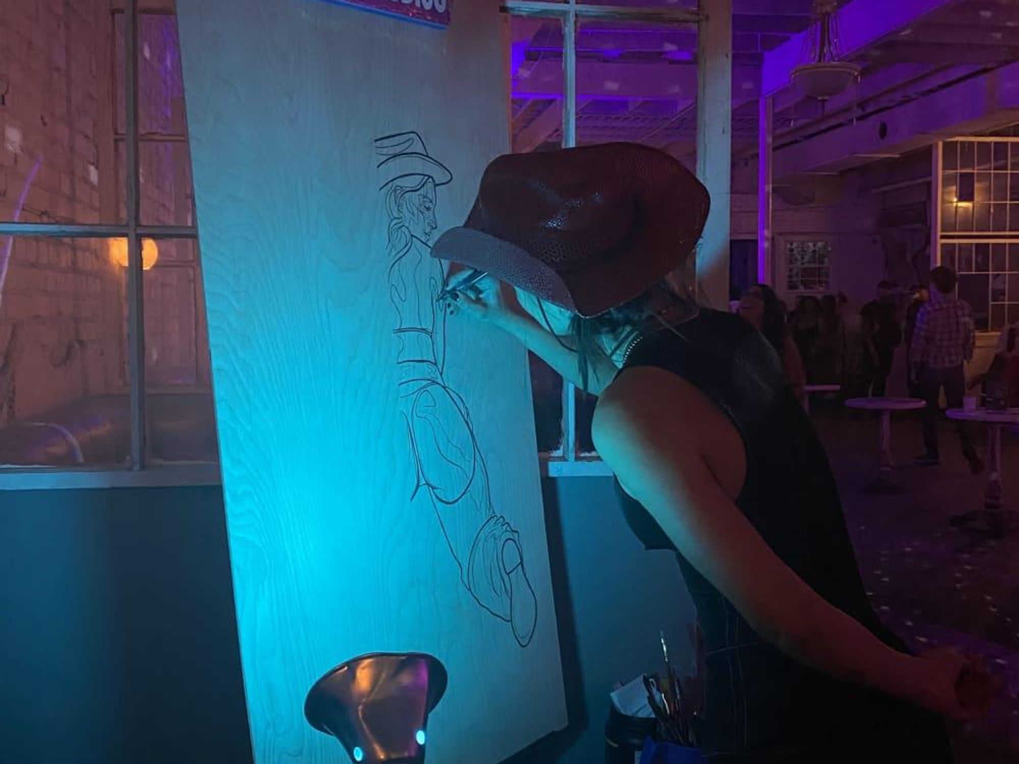 AJ Brooker works on a line drawing of a nude cowgirl at the Swan Dive during the "Saddle Up" event.