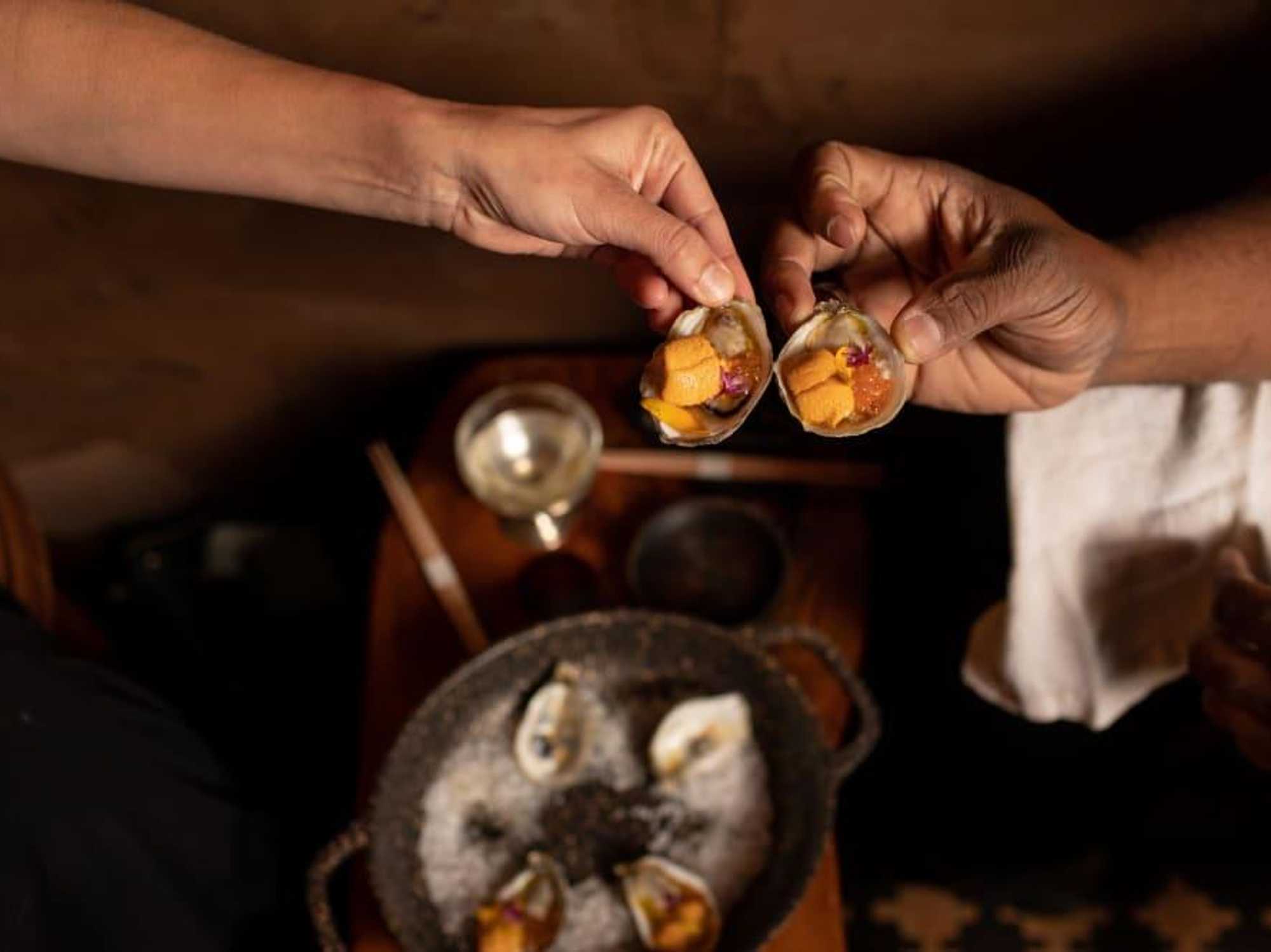 Diners hold uni in oyster shells with roe.