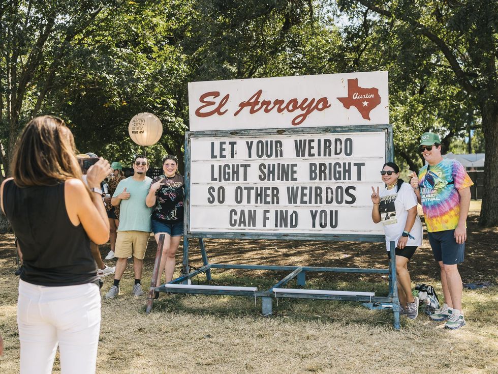 Fans post with a sign by El Arroyo at Austin City Limits Festival
