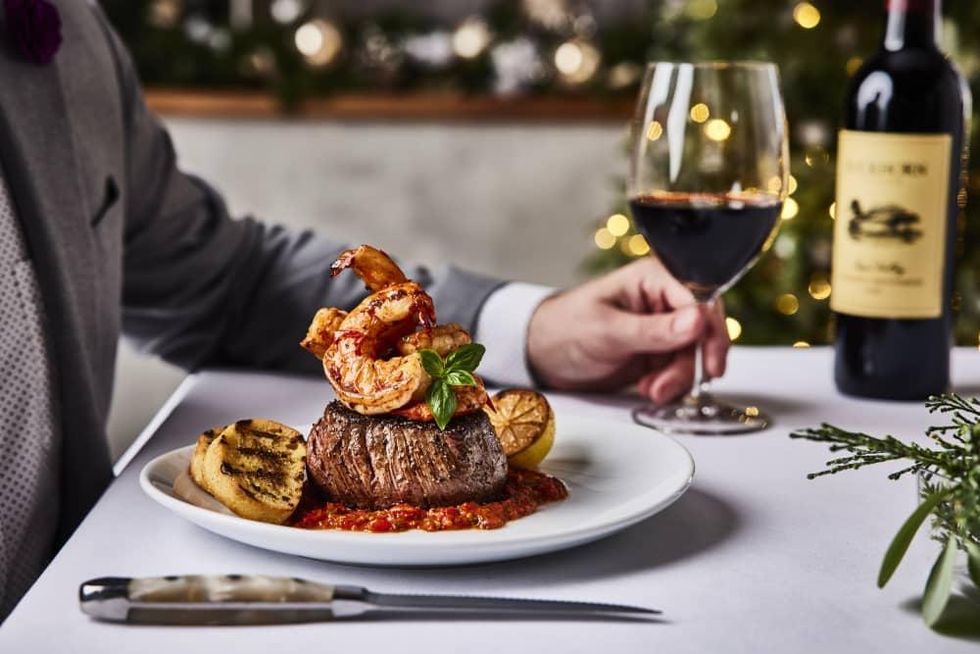 Filet mignon with a grilled shrimp on top and a glass of red wine.