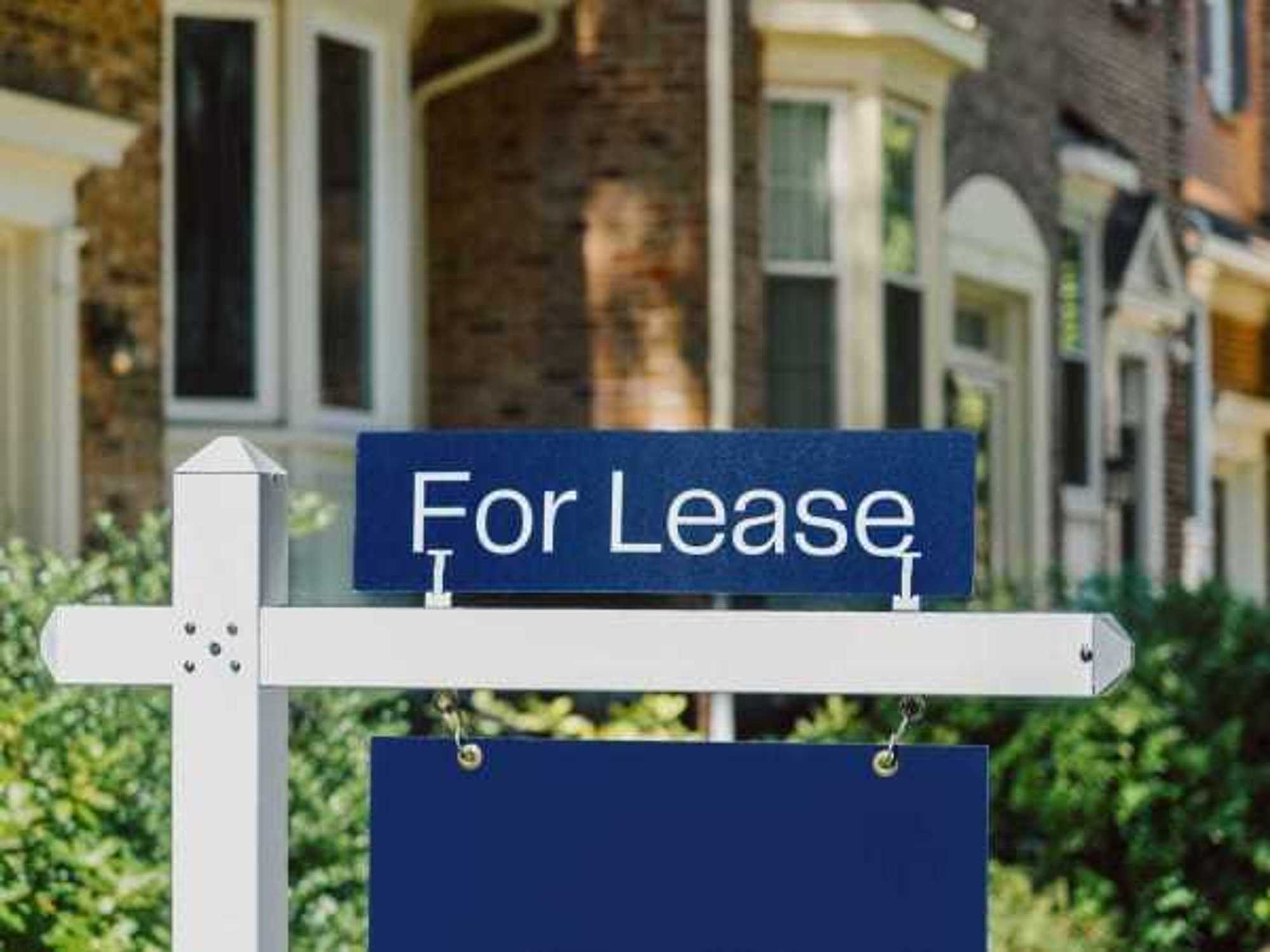 For Lease Real Estate Sign Hangs in Front Yard of House