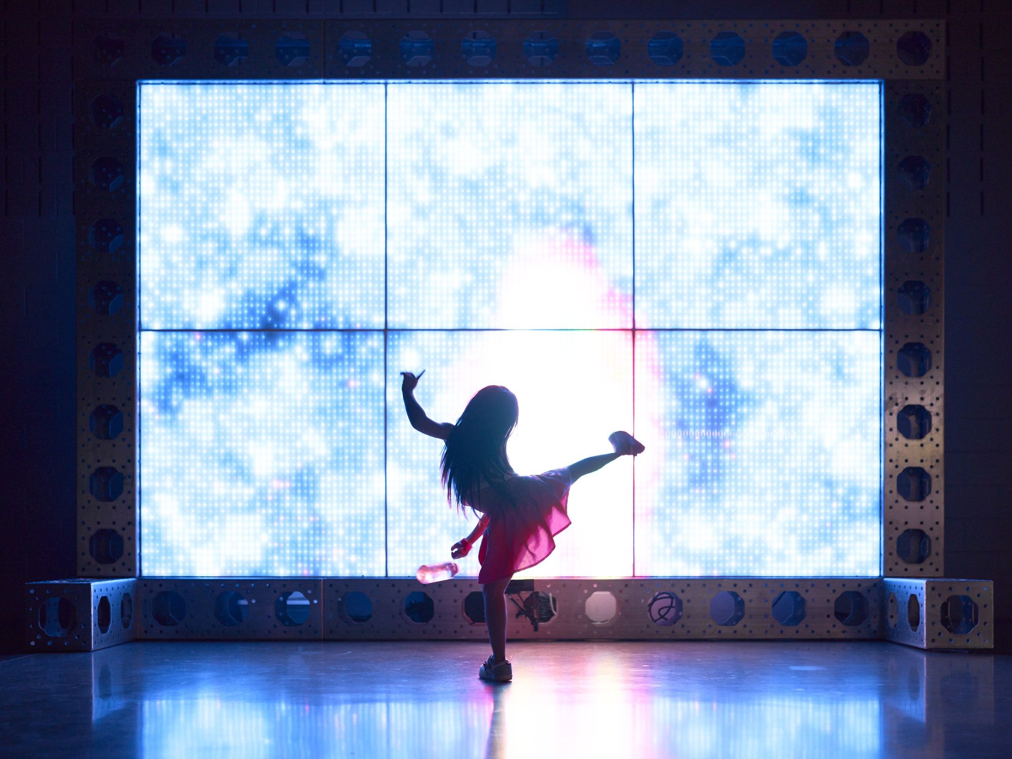 Girl dances in front of immersive art piece