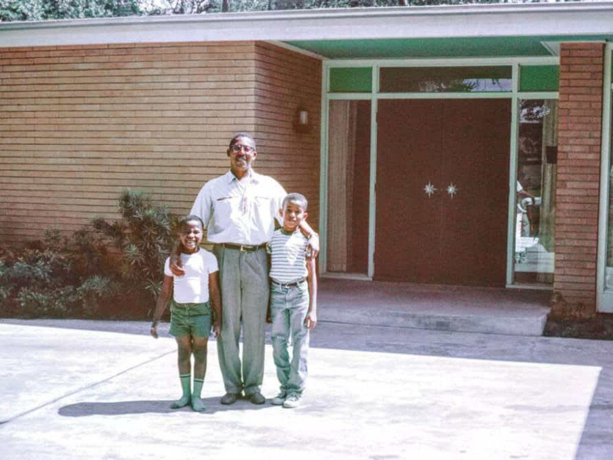 John S. Chase stands in front of his family home in Houston with two of his three children, Anthony (left) and John Jr. (right).
