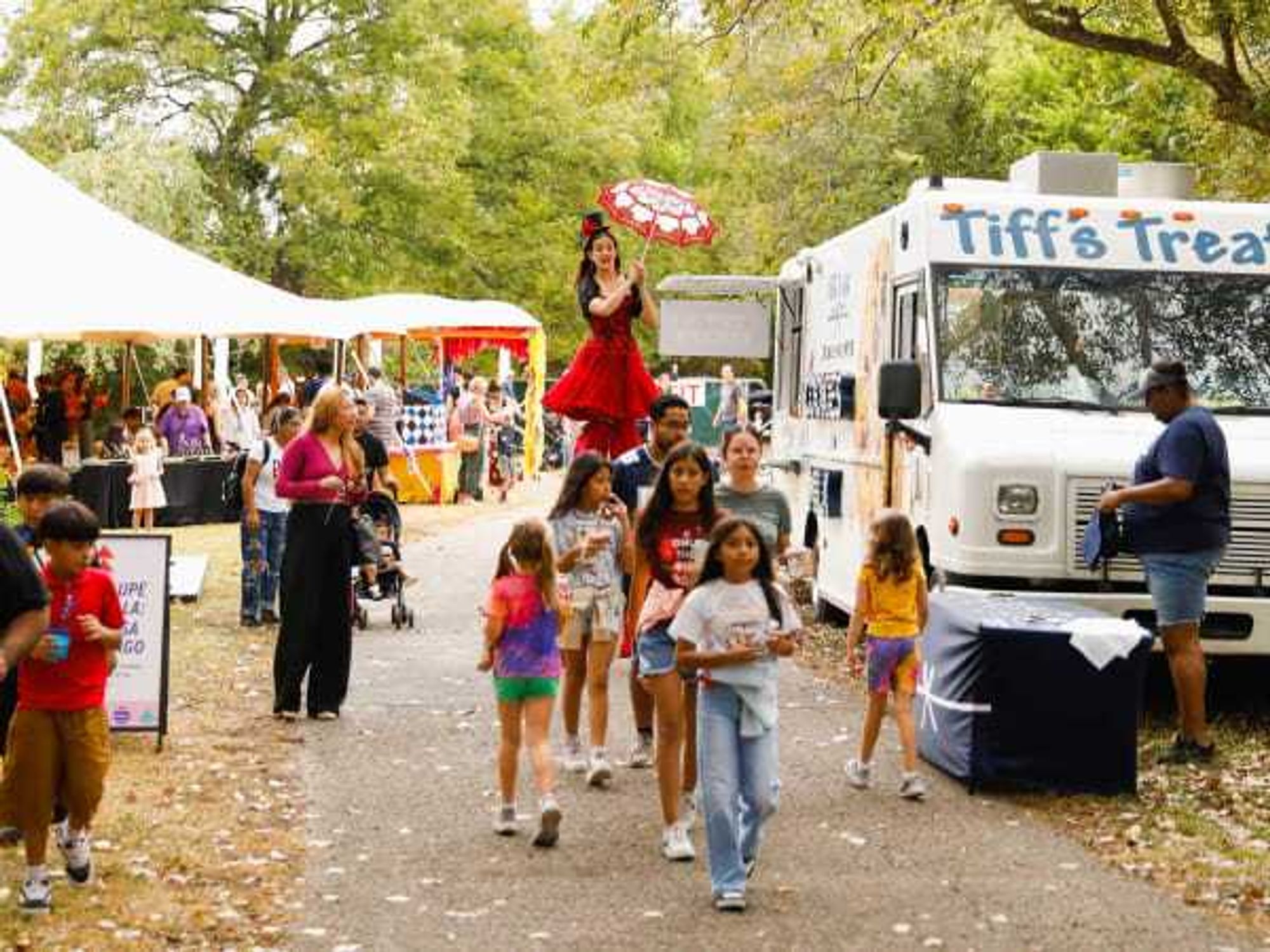 Kids, booths, and a performer on stilts at The Very 'Rary
