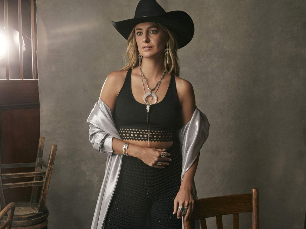 Lainey Wilson posing for the Yellow Rose x Kendra Scott by Lainey Wilson collection