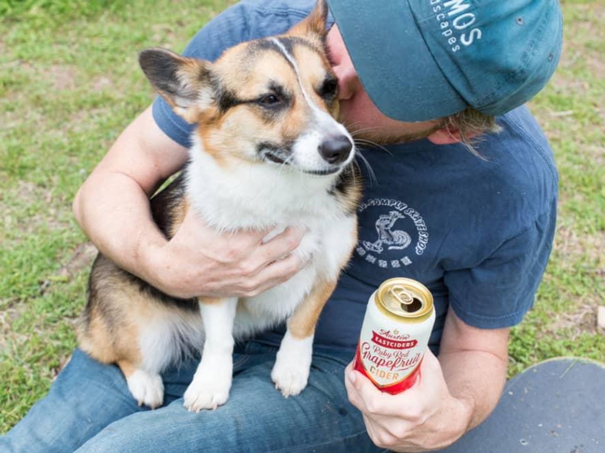 Man hugging dog while holding Austin Eastciders can