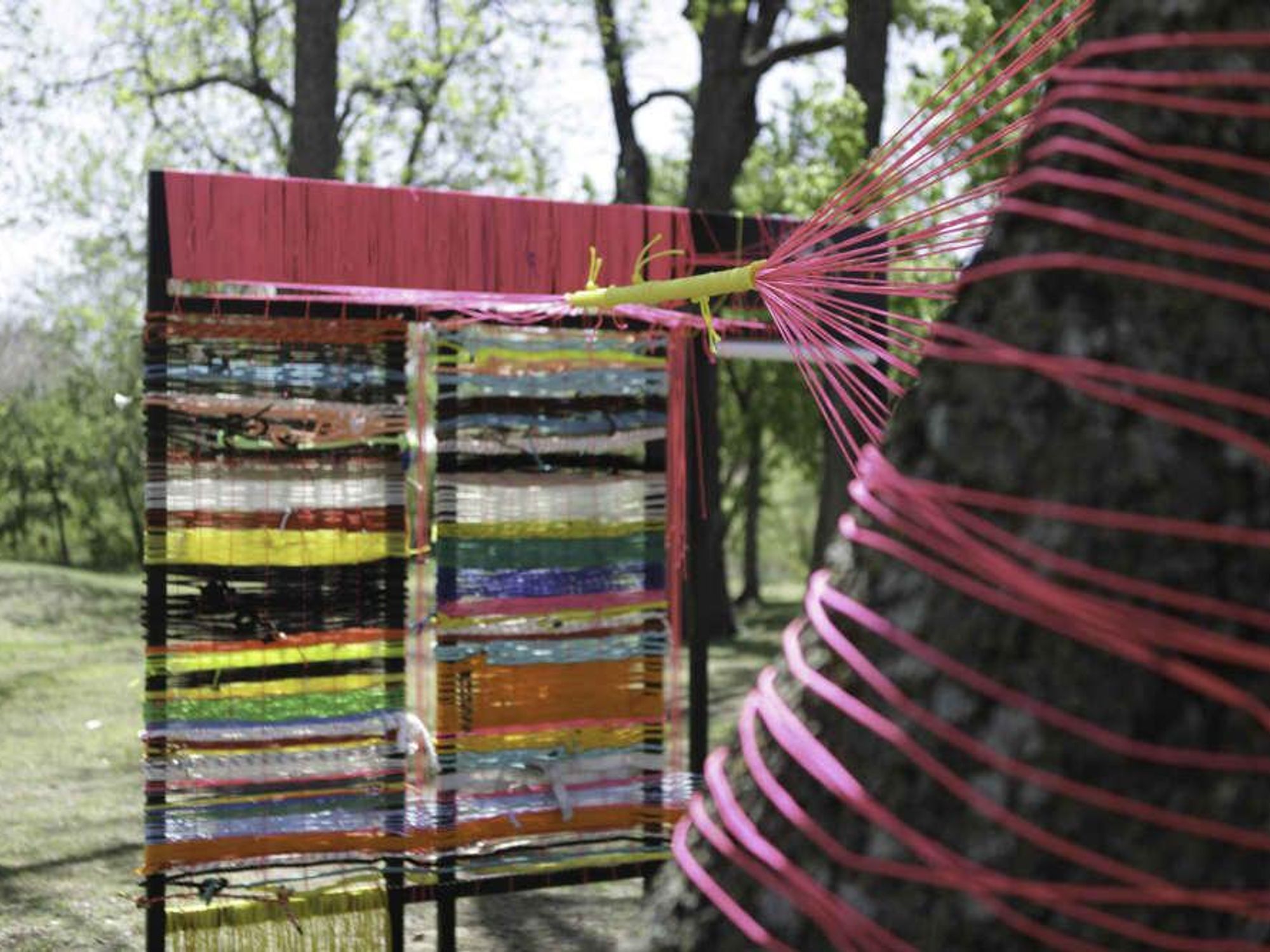 Mire + Mend, a community art project weaves colorful fabric and ropes between trees outside the Elisabet Ney Museum.