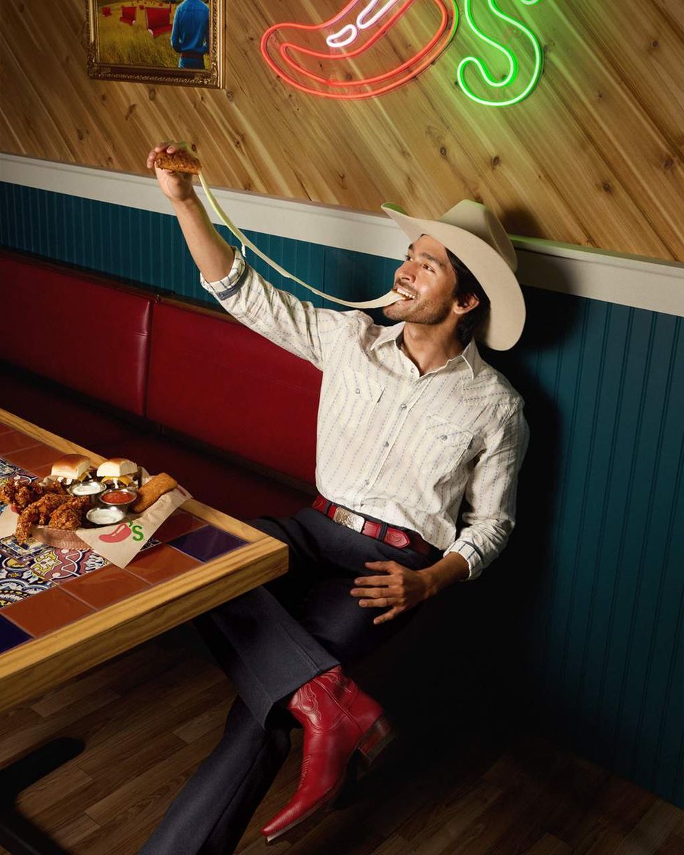 Model wearing Chili\u2019s x Tecovas Booth Boot and Booth Belt