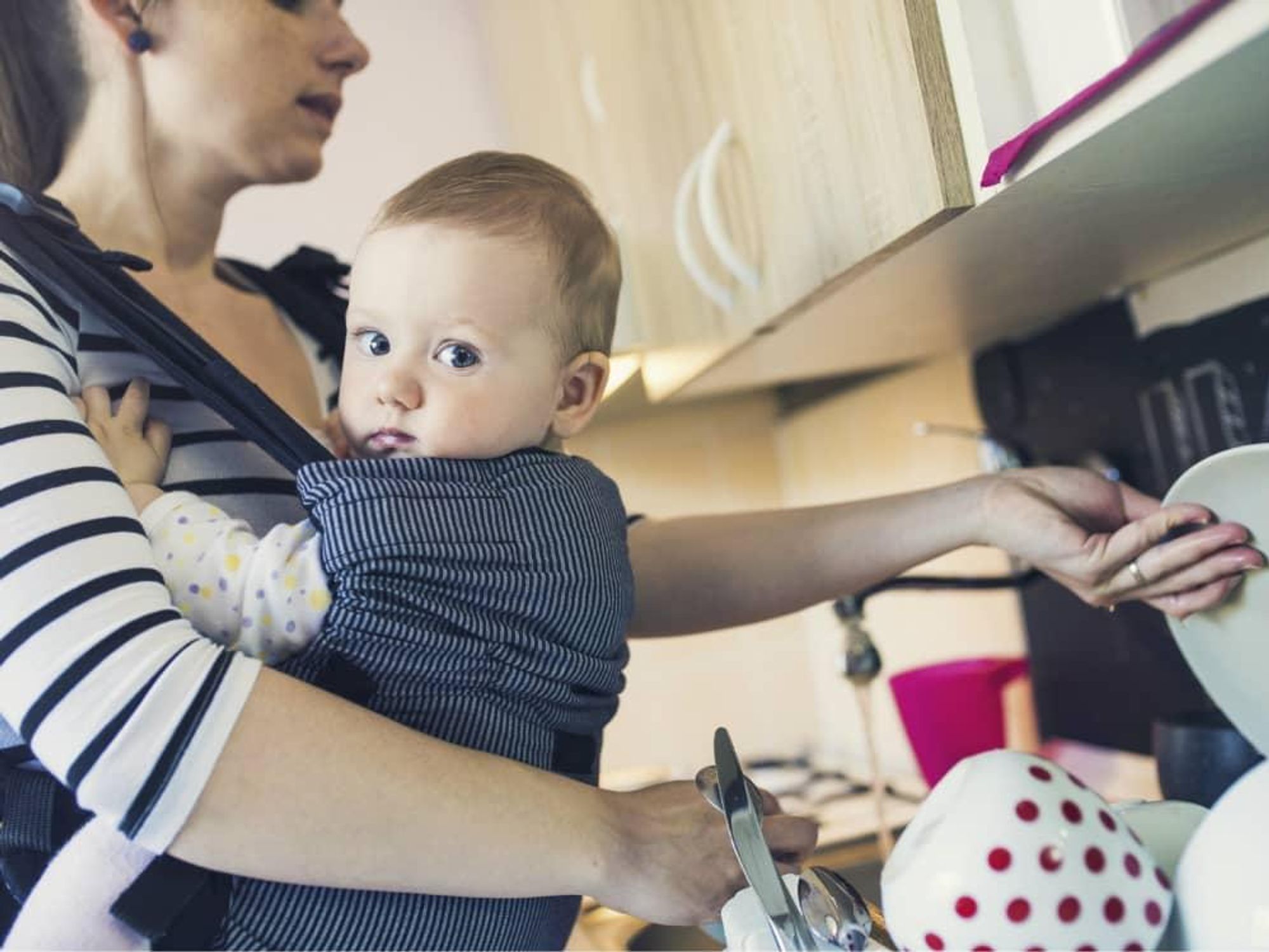 Mom washing dishes while holding her baby