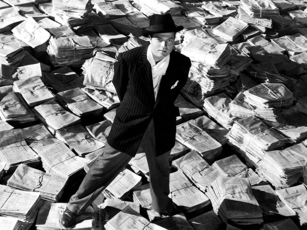 Orson Welles standing on mound of newspapers to promote Citizen Kane