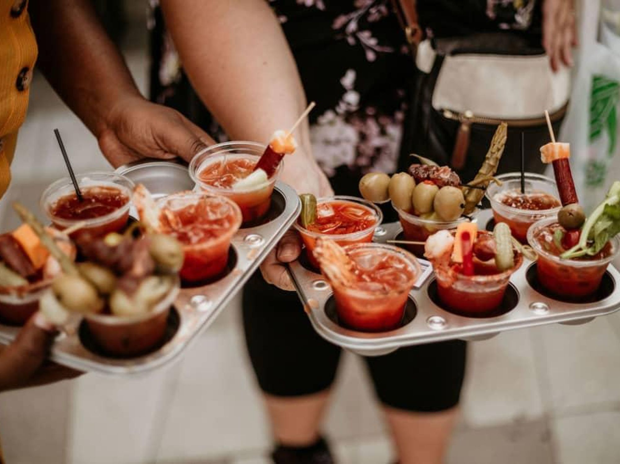 People carry trays of Bloody Mary's with different garnishes