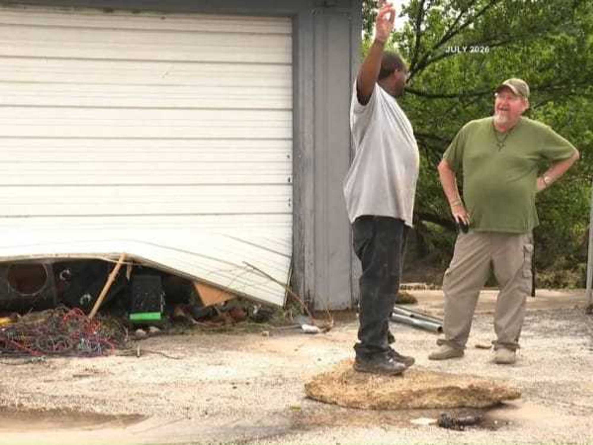 People stand in front of damaged garage