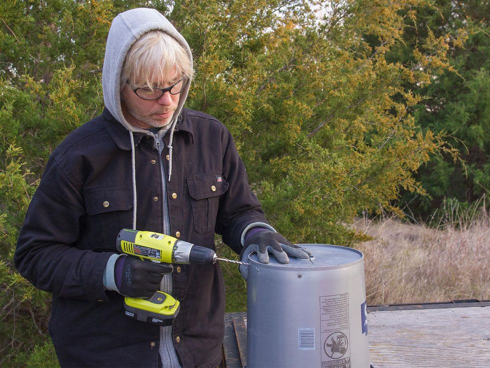 Photo of marshall Hinsley drilling holes in Bokashi bucket.