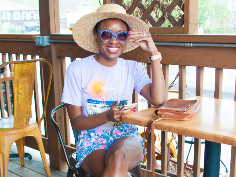Sakeenah Aleem wears tourist t-shirt, colorful shorts, and wide brimmed straw hat in Austin, Texas