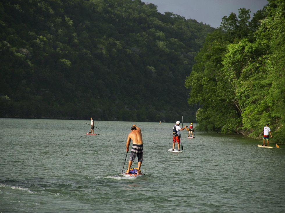 single paddleboarder on lake for Tyler's Dam That Cancer