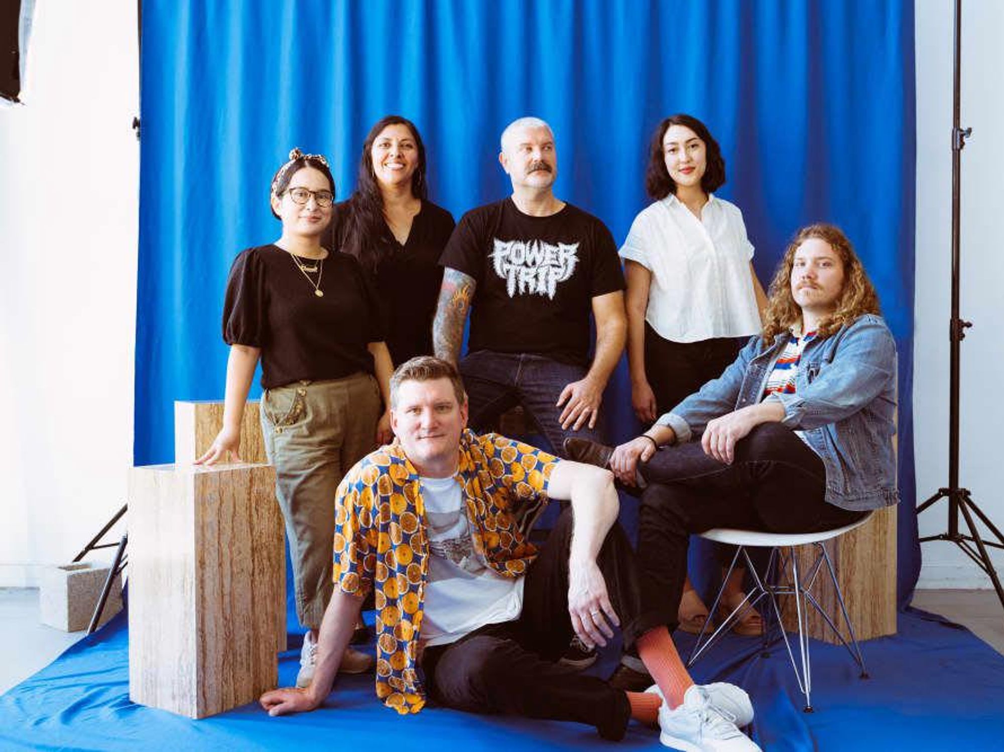 The team launching concert promotion and creative branding company Resound, sitting in front of a blue backdrop with photo equipment