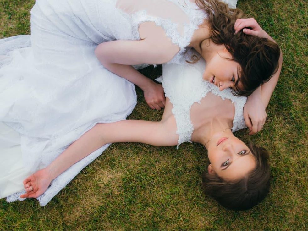 Two brides lying in the grass