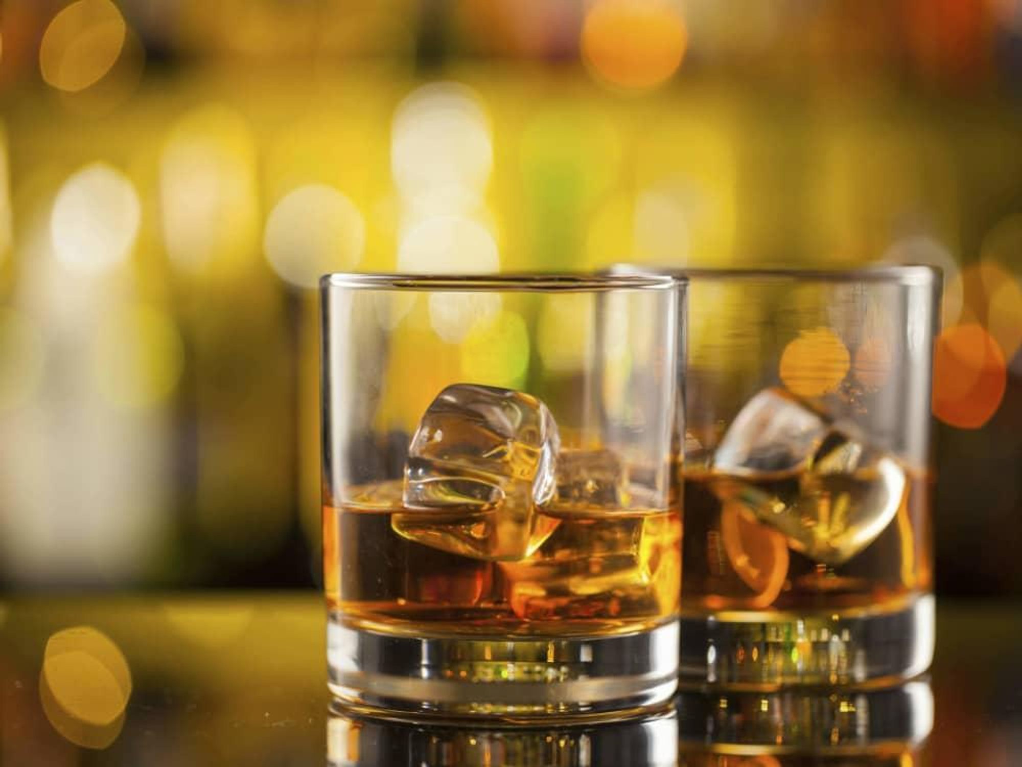 Two glasses of whiskey on a bar