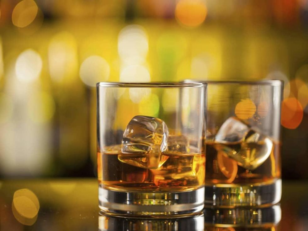 Two glasses of whiskey on a bar