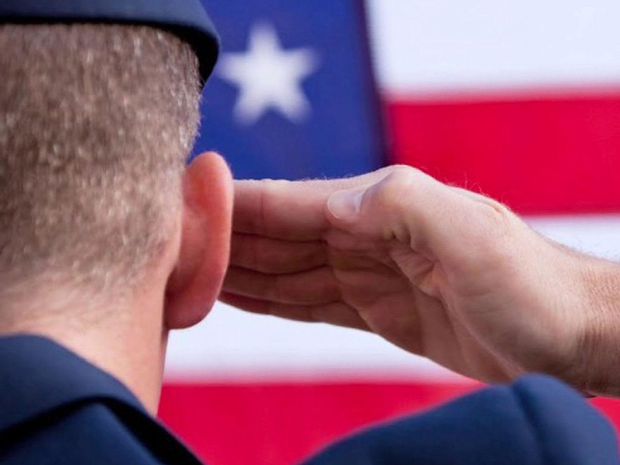 veteran military man saluting an American flag