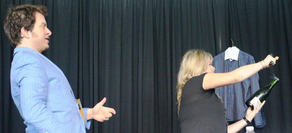 Wine critic Marc Oldman teaching an audience member how to saber a bottle of Champagne