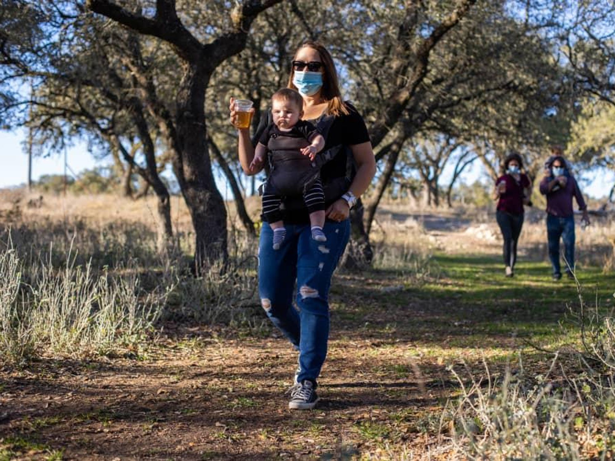 Woman walking with baby and holding a beer